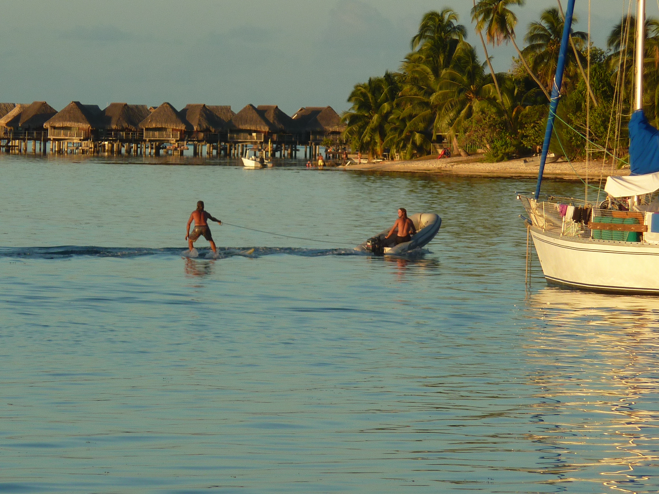 I drive the dinghy with Rob surfing behind. We're at Moorea, the stilt hotel in the background.
